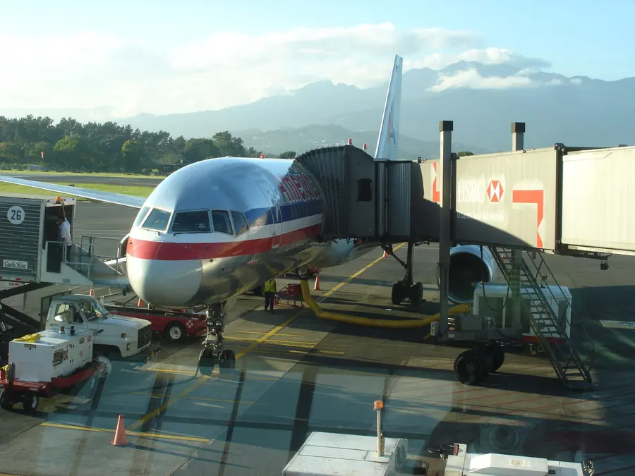 A plane at the gate of Juan Santamaría International Airport, with the mountains of the Central Valley behind
